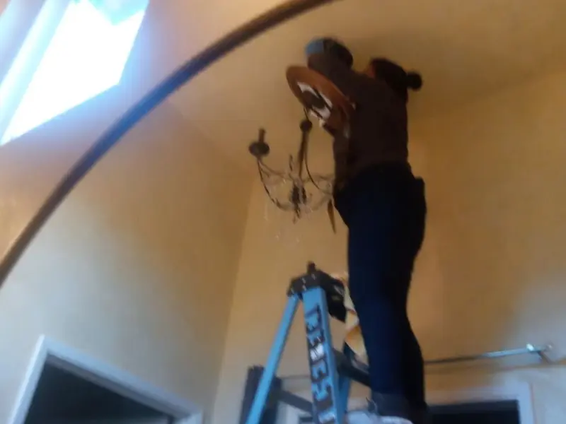 Electrician installing a chandelier in a Tilton residence
